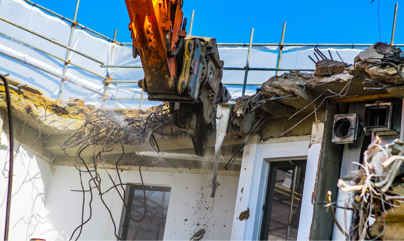 J Mould excavator crusher breaking a reinforced concrete roof slab inside sheeted scaffolding