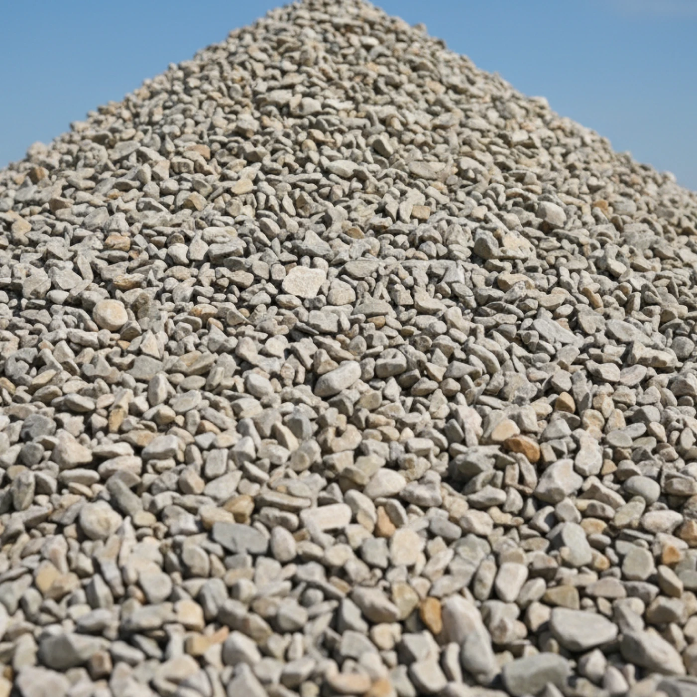 Heap of clean pale grey J Mould gravel against a clear blue sky