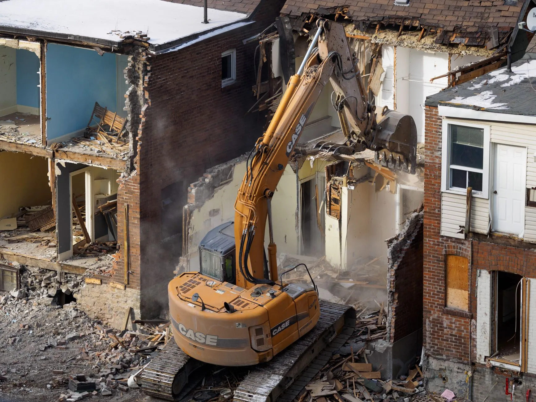 J Mould house demolition: yellow CASE excavator taking down a two-storey house