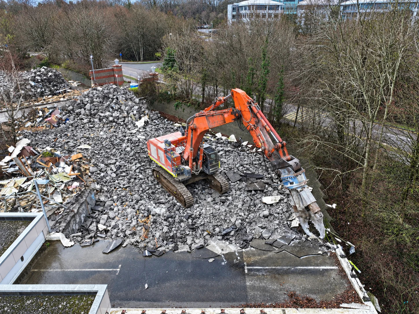 Orange J Mould excavator with a demolition crusher on a heap of broken concrete on a car park deck