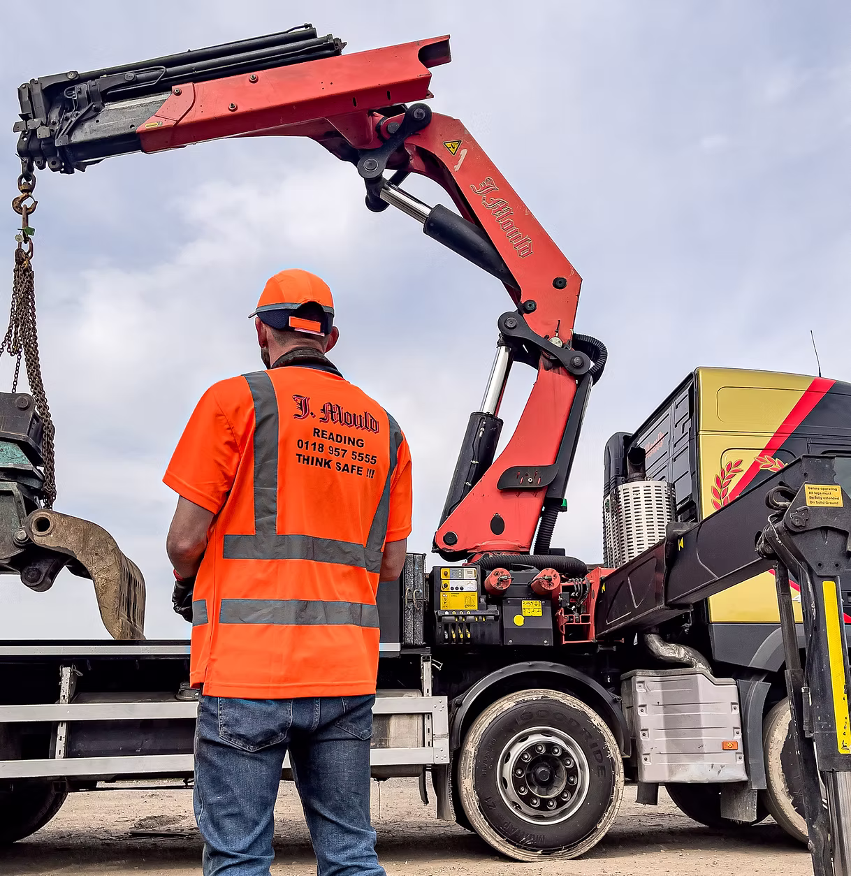 Operator in hi-vis printed 'J. Mould Reading 0118 957 5555 Think safe!!!' watching a red lorry-mounted crane