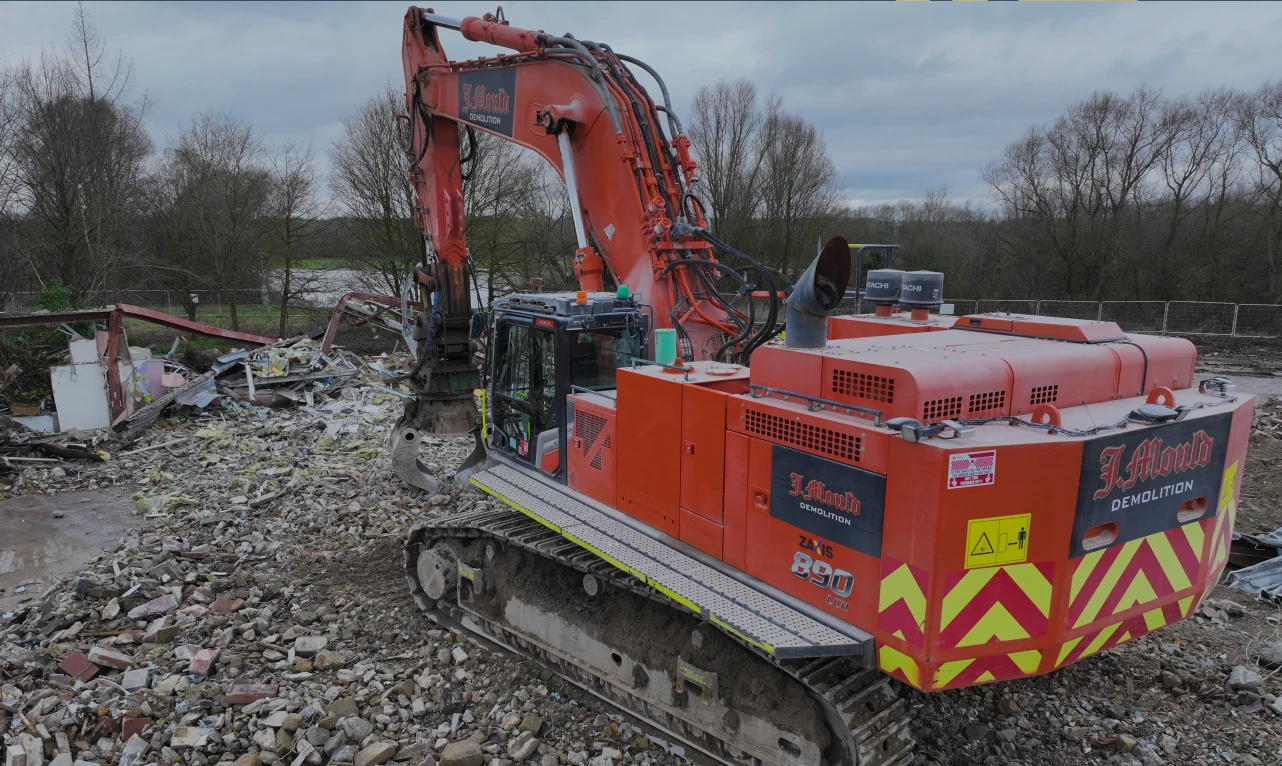 Red J Mould HIAB crane lorry lifting a steel container at a building site