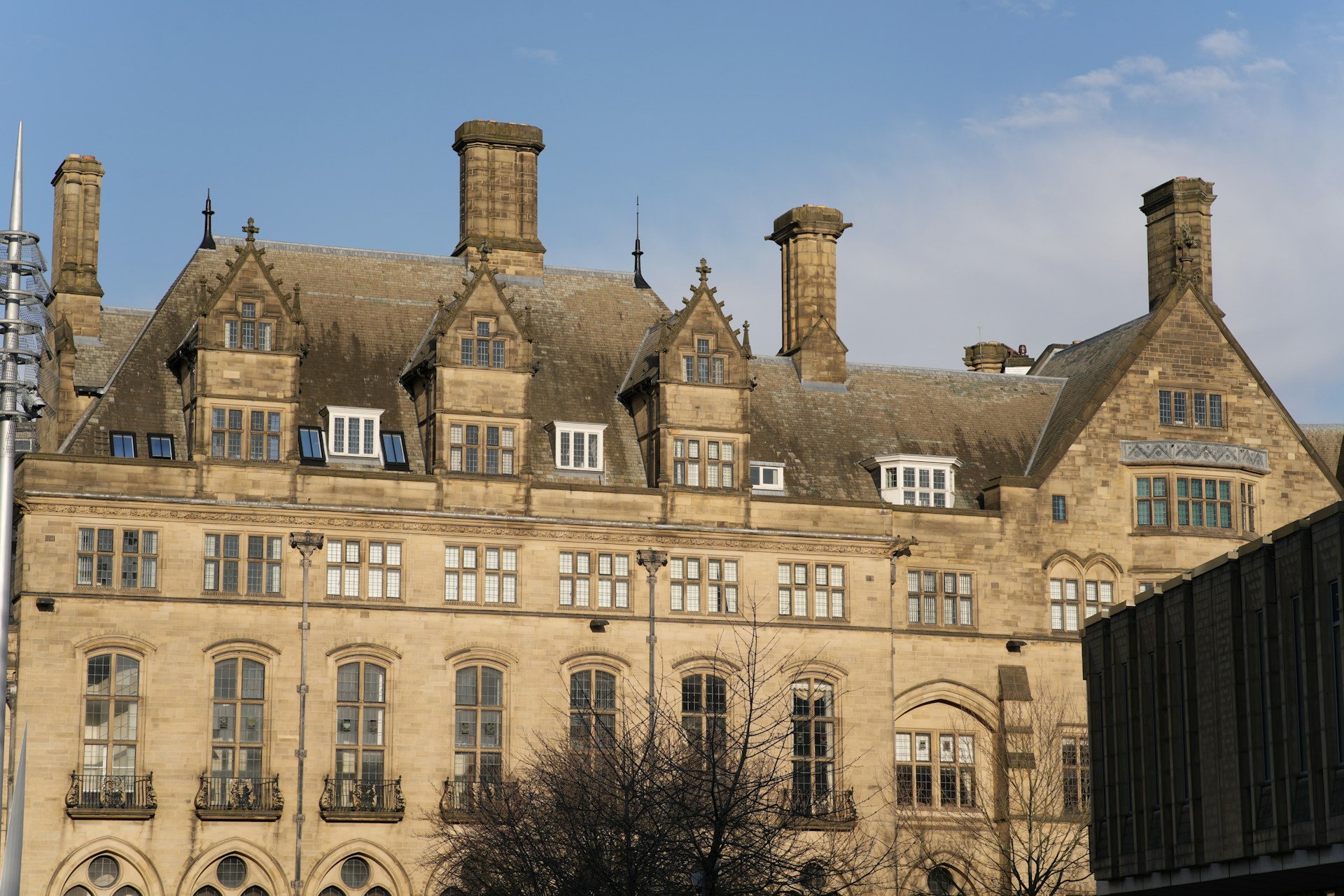 Victorian sandstone building with gabled dormers and tall chimneys against a blue sky