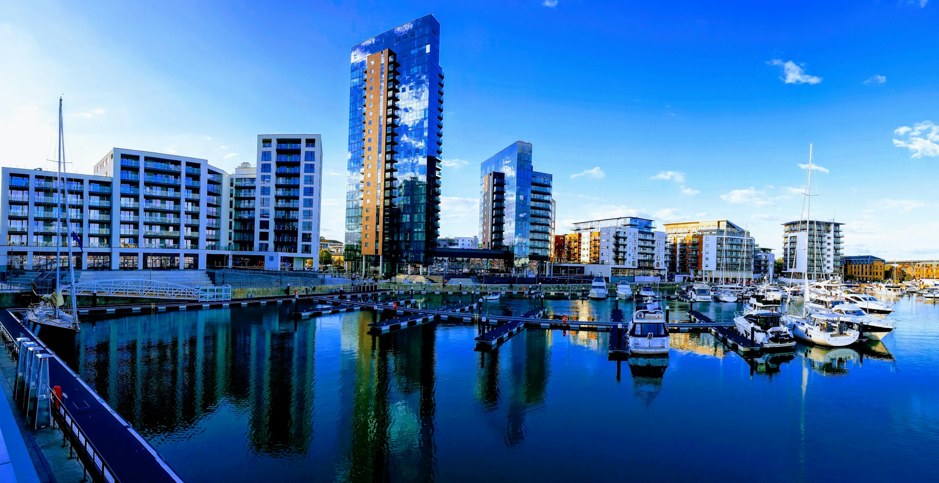 Glass apartment towers and yachts reflected in a Southampton marina, a city J Mould covers for demolition
