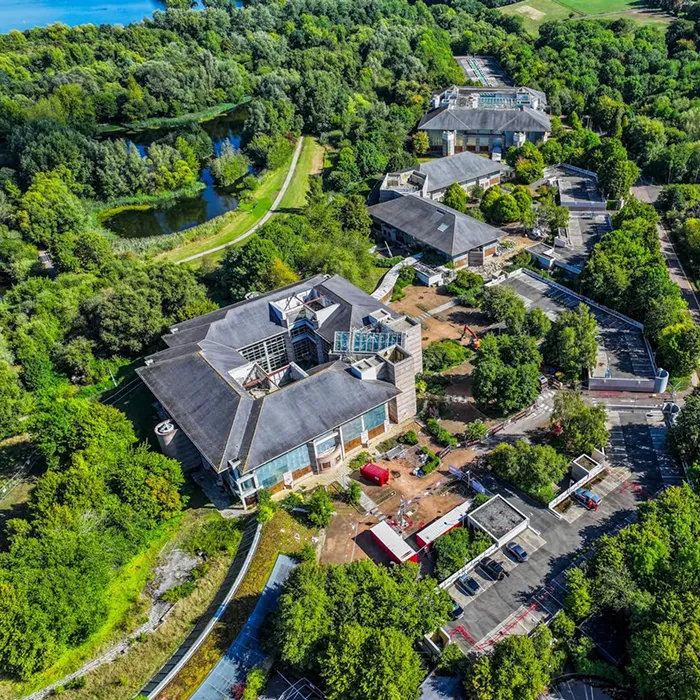 Aerial view of a landscaped office campus surrounded by woodland and a lake