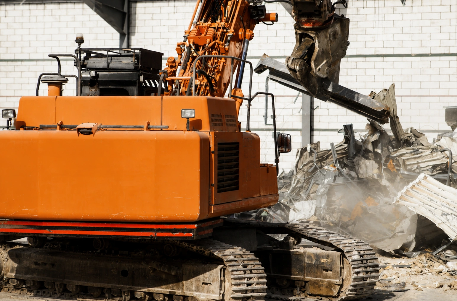 Orange J Mould excavator with a demolition shear tearing into a metal-clad building