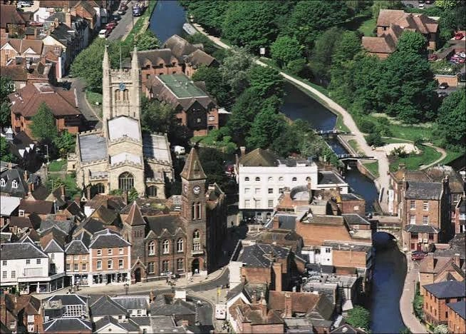Aerial view of a Berkshire town centre with a church tower and river, in J Mould's skip hire area