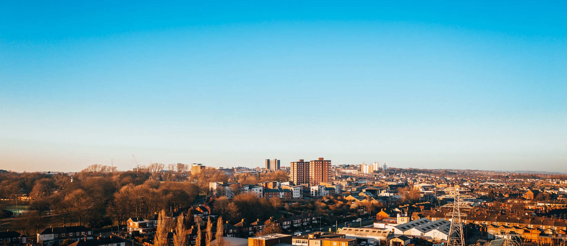 Town skyline in low winter sun with tower blocks and terraced streets, an area J Mould covers for demolition