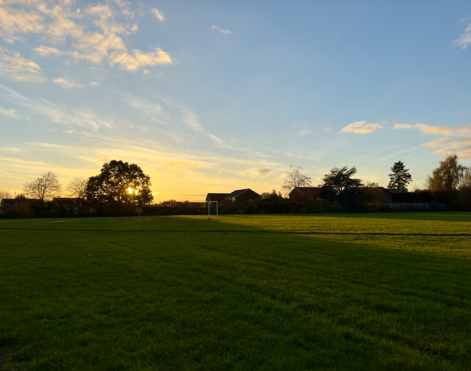Playing field with a football goal at sunset, houses beyond, in an area J Mould covers for demolition