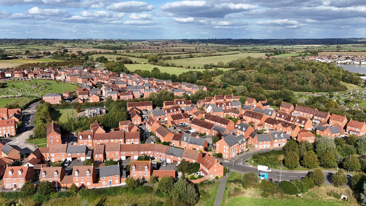 Aerial view of a red-brick housing estate with fields and a lake, an area J Mould covers for demolition