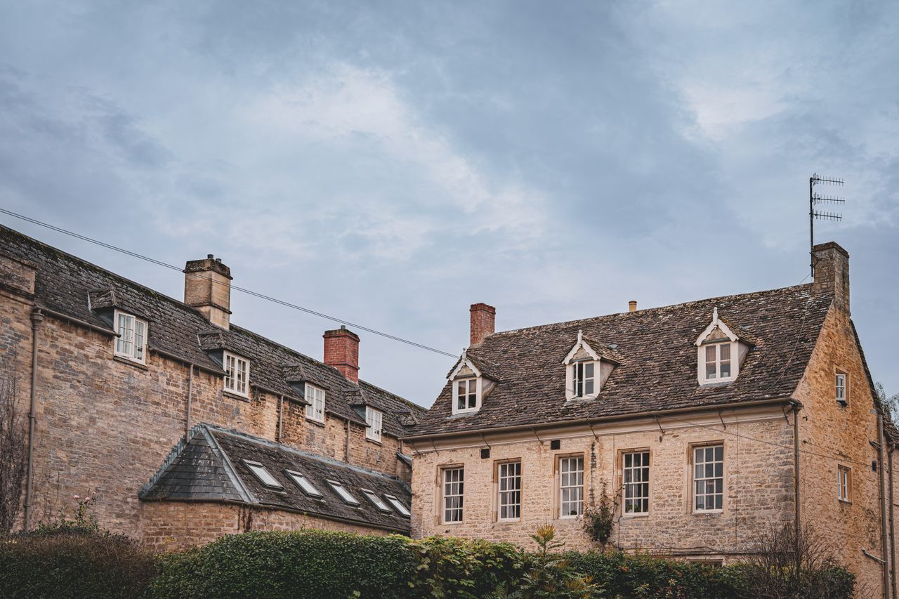 Honey-coloured stone houses with dormer windows and stone-tiled roofs under a grey sky