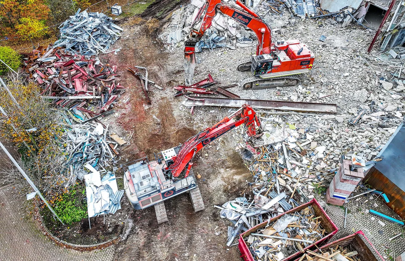Overhead view of two orange J Mould excavators sorting demolition rubble, steel and timber into piles and skips